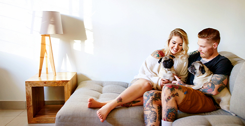 Couple with Tattoos laying on couch with two dogs