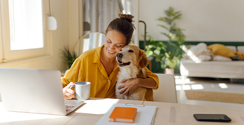 Woman at her desk with her dog in her bedroom