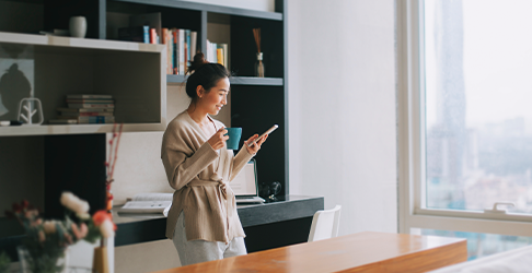 A woman standing in a modern interior house browsing her phone